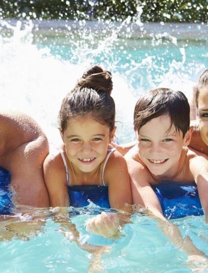 Famiglia felice sorride e gioca insieme in piscina, spruzzi d'acqua e gioia.