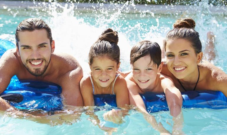 Glückliche Familie lächelt und spielt im Pool, Wasserspritzer und Freude.
